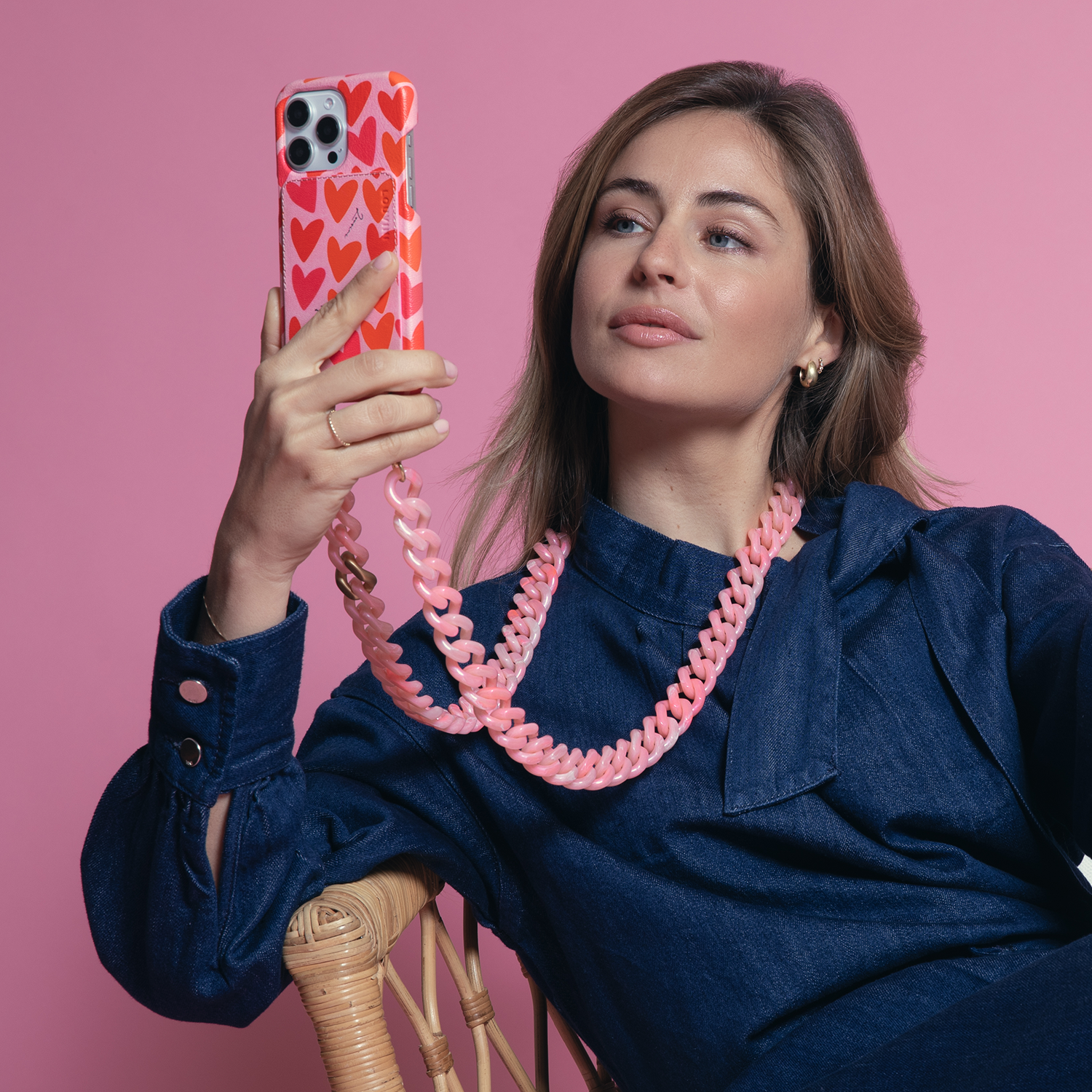 coque iphone en cuir imprimé coeurs rose et rouge et chaine bandoulière de téléphone à maillons rose